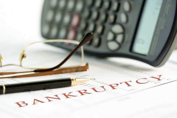 Bankruptcy written on sheet of paper with glasses, pen and calculator in view