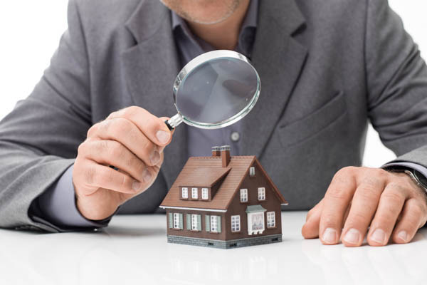 Conveyancing - man inspecting house with magnifying glass