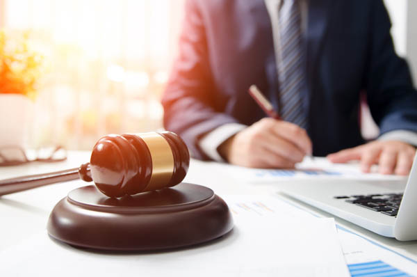 Litigation lawyers - male lawyer working behind desk with a wooden gavel sitting on top.