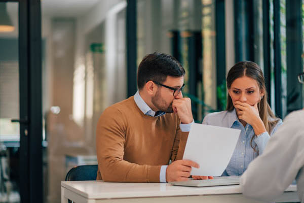 Sale of business contract mistakes - couple looking upset and surprised at mistake made